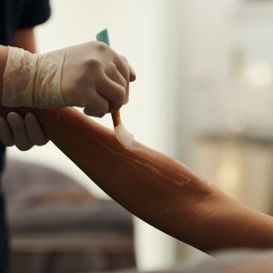 Closeup image of beautician applying gel on body of client before epilation
