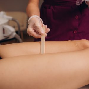 Beautician makes depilation young woman on her feet with wax, liquid sugar. High quality photo