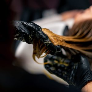 close-up of a hairdresser applying paint to a client's wet hair in beauty salon makeover