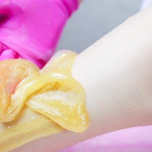 close-up of the master's hands removing hairs with sugar paste