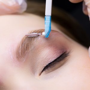 laying out the eyebrow hairs after the eyebrow lamination procedure, the master combs the eyebrows with a brush