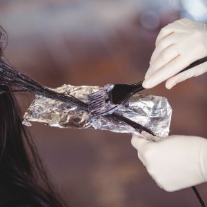 Hairdresser dyeing hair of her client at a salon