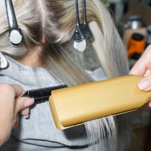 Keratin hair straightening with a professional iron. Hairdresser performing hair treatment. Spa salon concept, hairdressing
