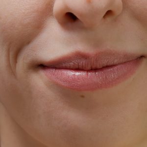 Macro shot of female model smiling and moving lips on camera, showing white teeth and candid smile. Happy woman with beautiful mouth and facial expressions, natural skin. Close up.