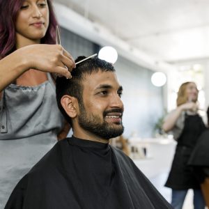 Man getting a haircut from a hair stylist at a barber shop