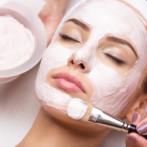 Young beautiful woman receiving  facial mask in spa beauty salon