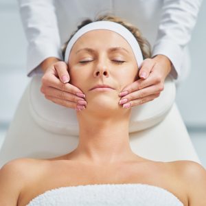 Young nice woman having face massage in spa. High quality photo